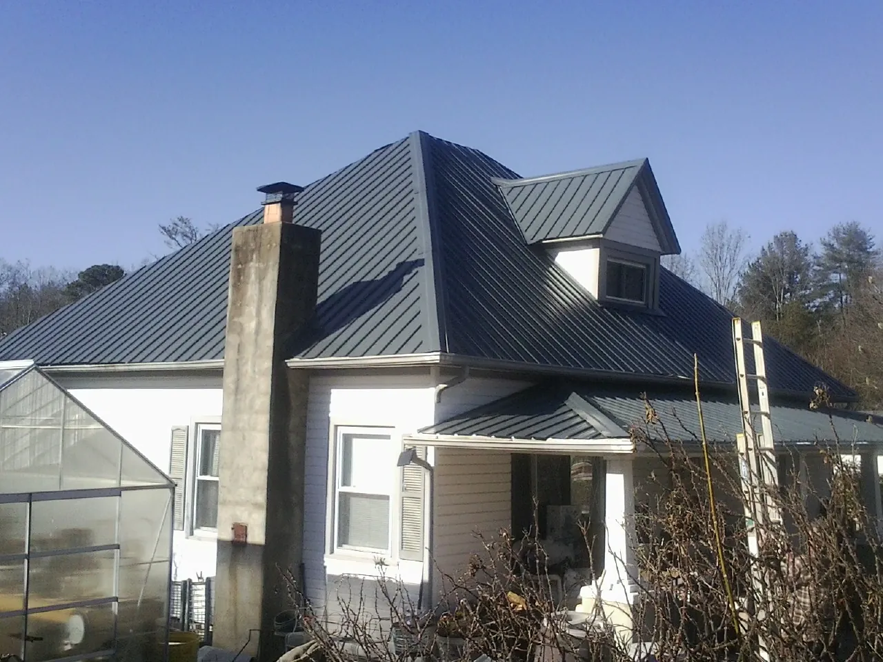 Dark blue standing seam metal roof on a white farmhouse with dormer — Slate & Tile Roof Repair by Roofing Brothers in Marysville