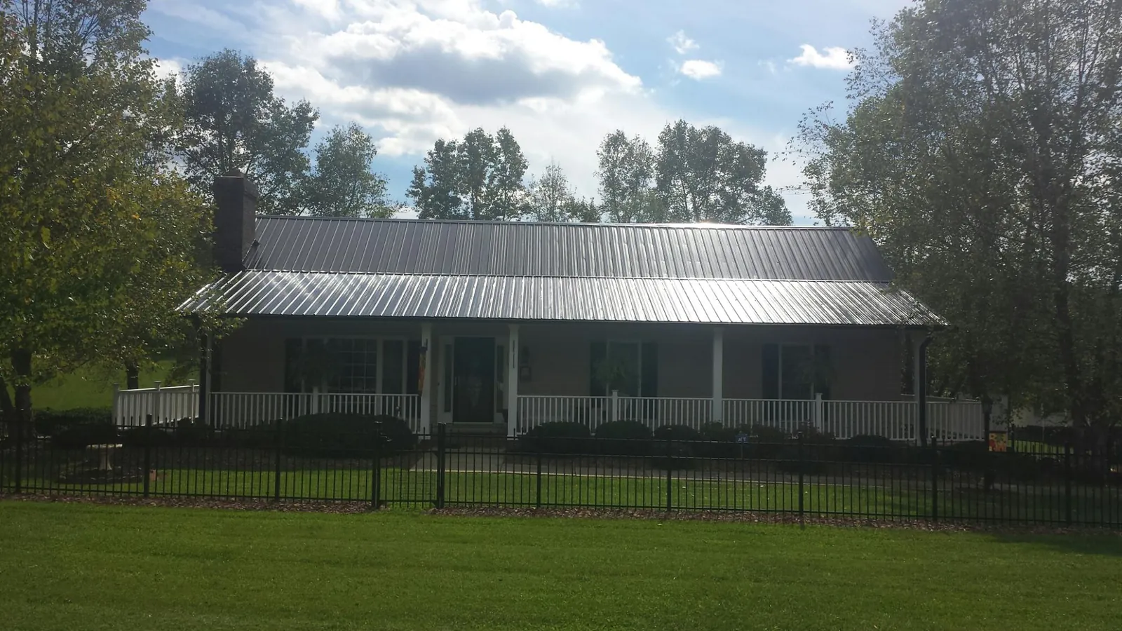 Gray metal roof on a brick ranch with a full width front porch — Gutter Guard Installation work by our crew in Marysville